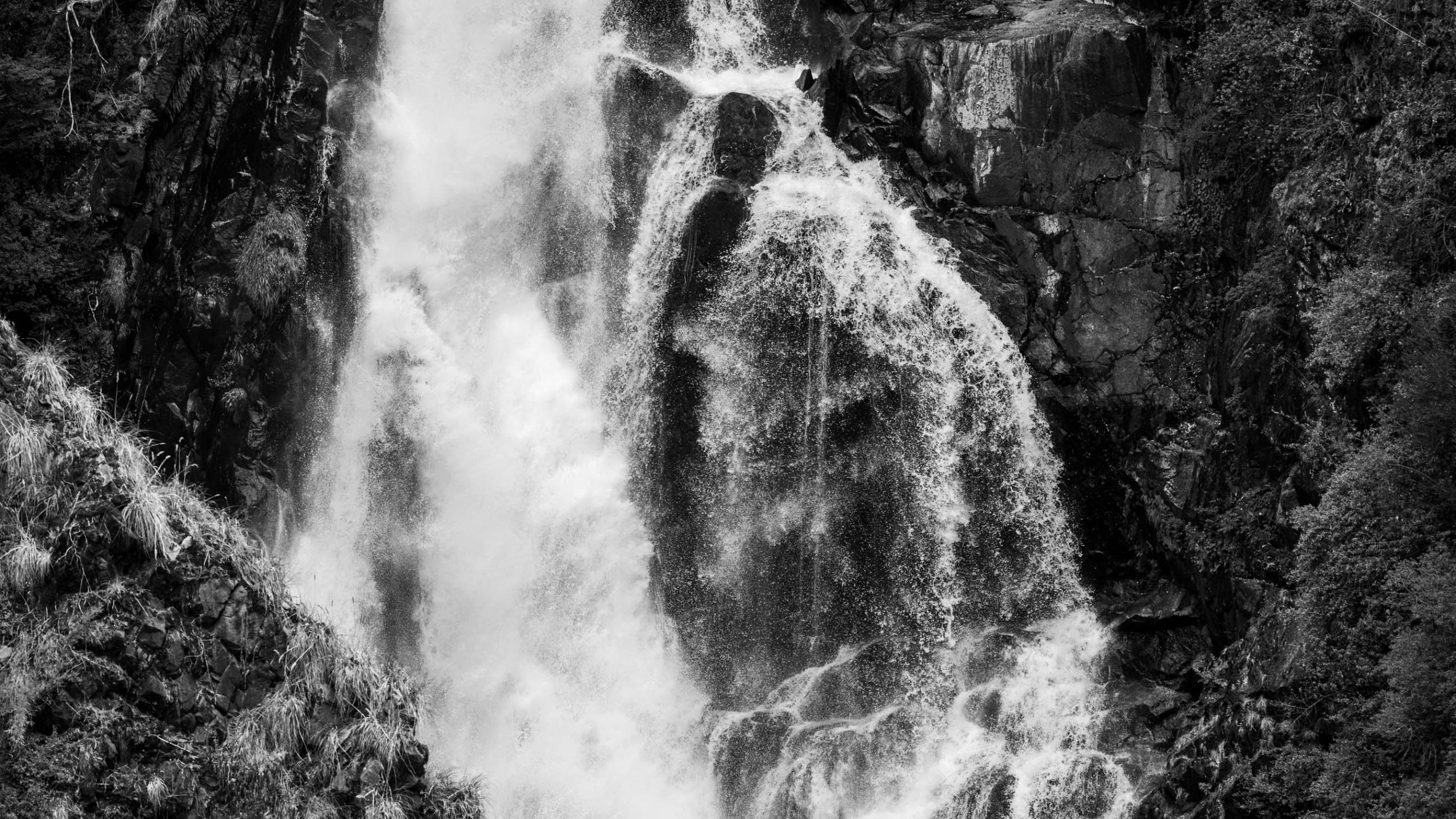 Cascada que cae entre rocas, en blanco y negro
