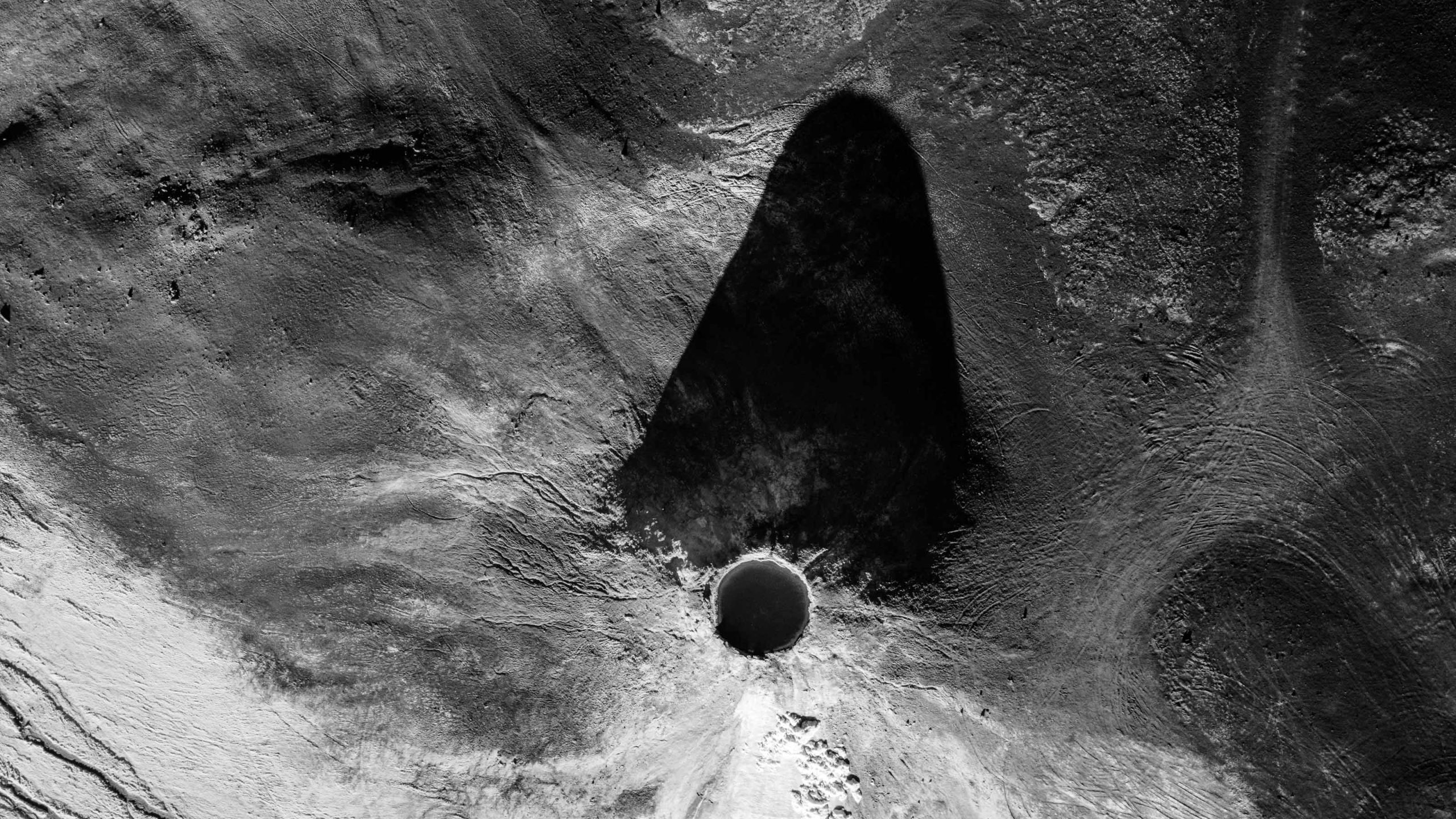 Vista aérea de una formación de roca y su sombra sobre el terreno, en blanco y negro